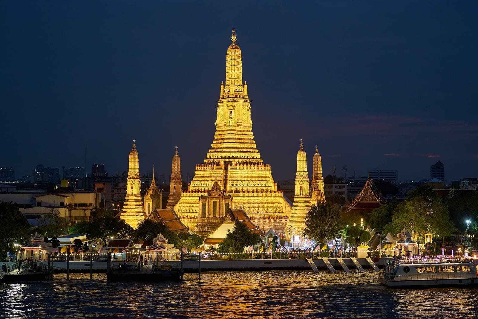 Wat Arun illuminated beside the river in Bangkok